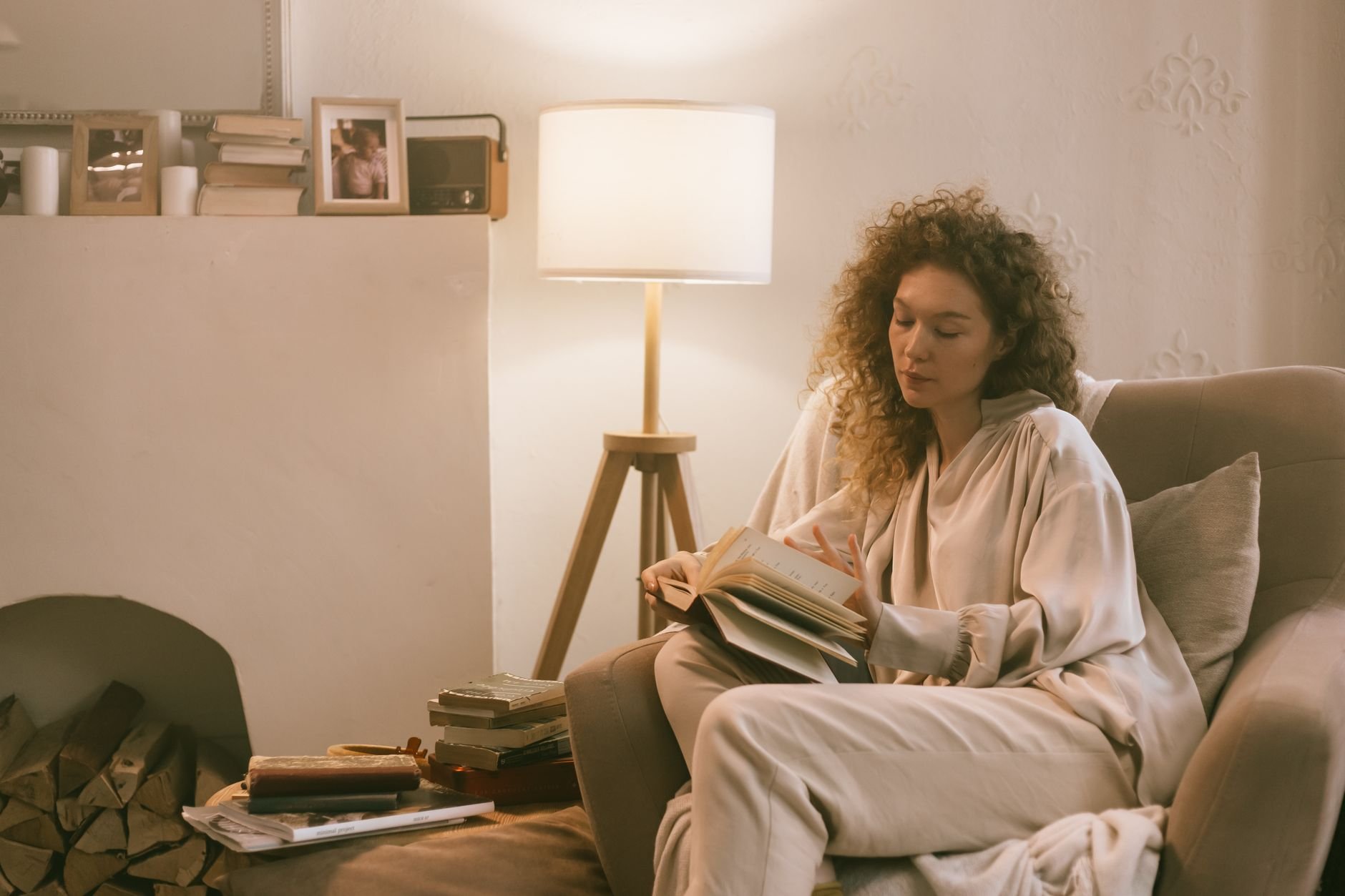 Woman with curly hair reading a book in a cozy living room setting, embracing relaxation and comfort.